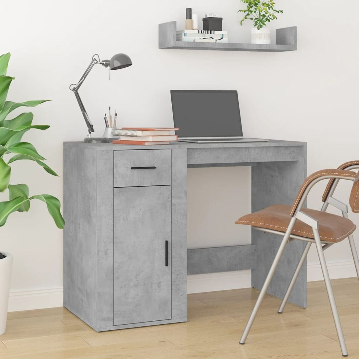 Ein grauer Betontisch mit Schublade und Tür. Ein Laptop, eine Lampe und andere Gegenstände auf dem Tisch.