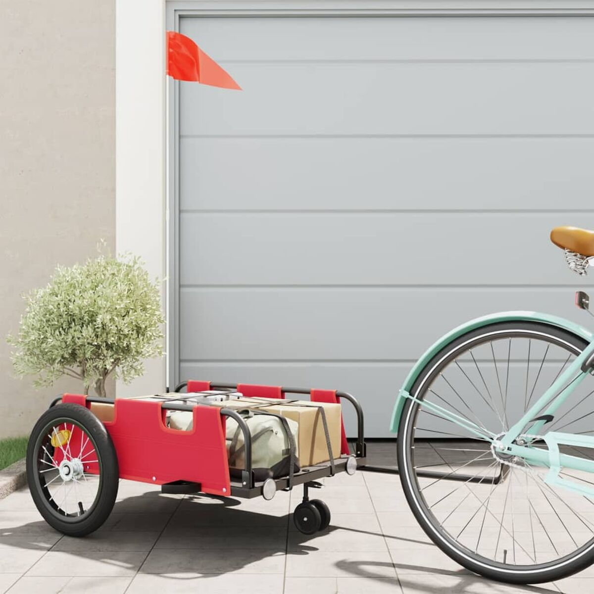 Roter Fahrradanhänger mit Kartons, befestigt an einem hellblauen Fahrrad, neben einer Garage.