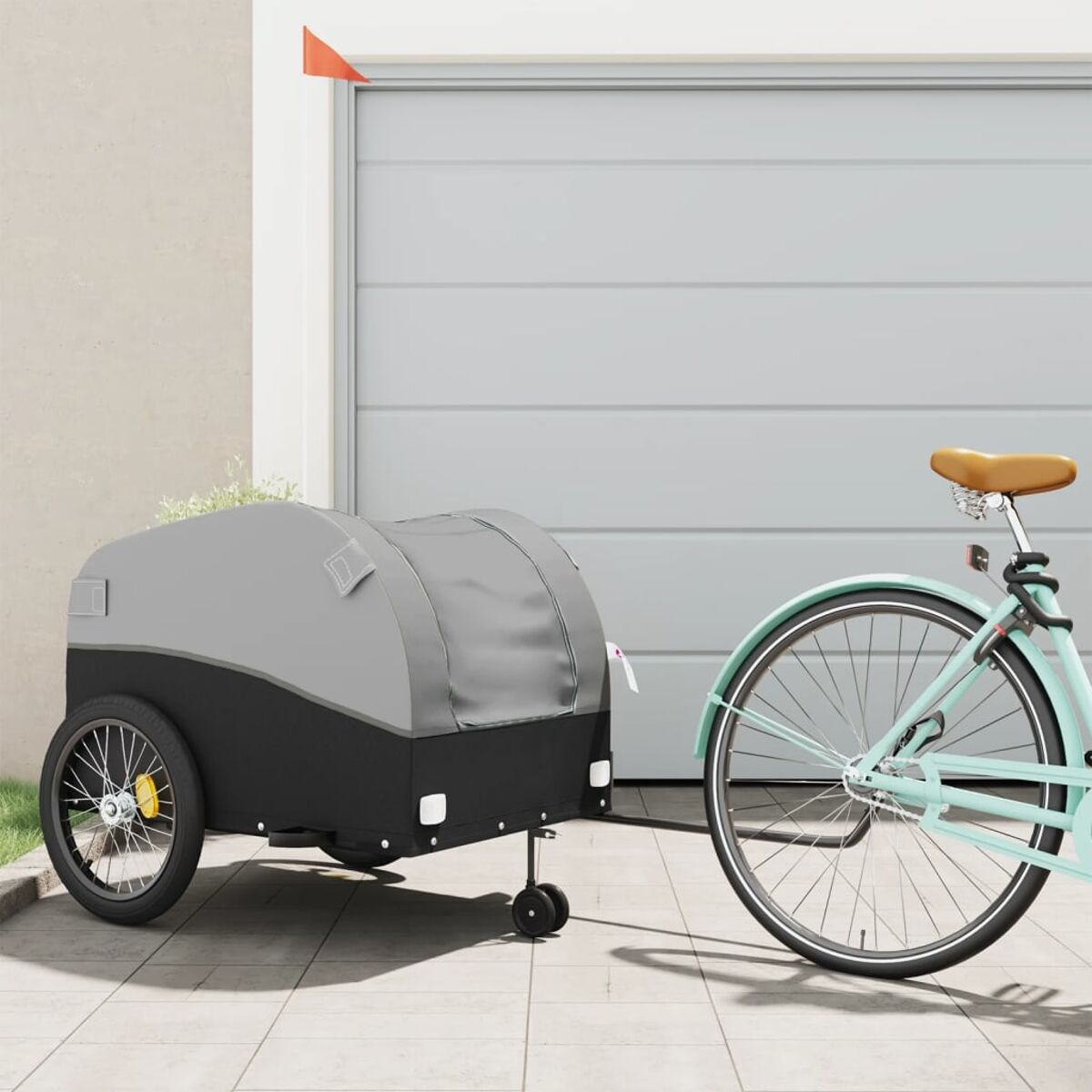 Ein Fahrrad zieht einen grau-schwarzen Fahrradanhänger. Der Hintergrund ist eine hellfarbige Garage.