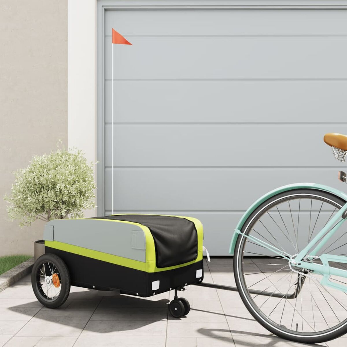 Fahrradanhänger mit grün-schwarzem Körper, gezogen von einem Fahrrad vor Garagentor.