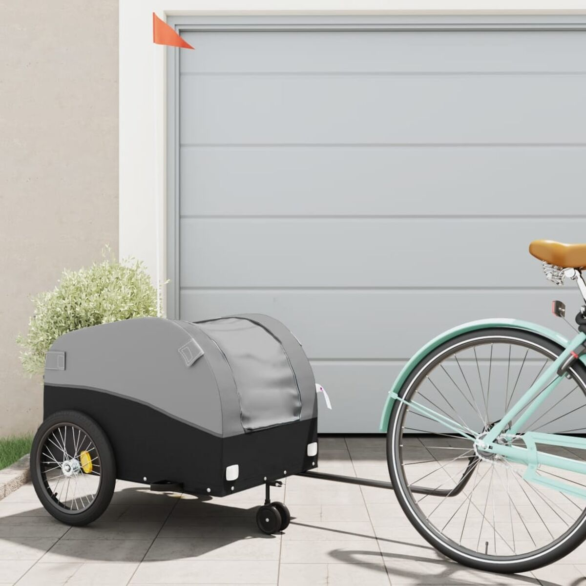 Fahrrad mit grau-schwarzem Anhänger, in der Nähe einer Garage.