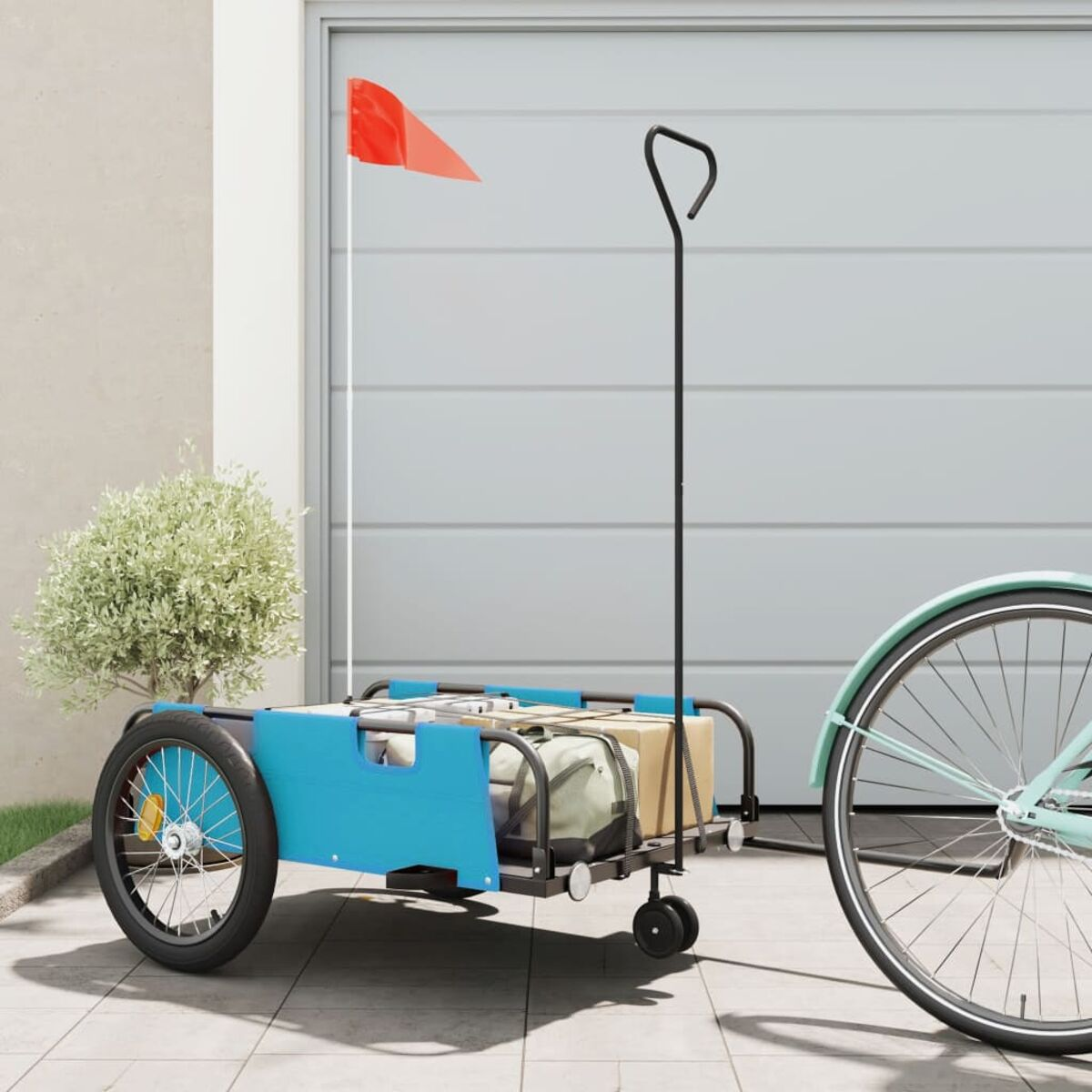 Blauer Fahrradanhänger mit Flagge und Boxen. Fahrrad und Garage im Hintergrund.