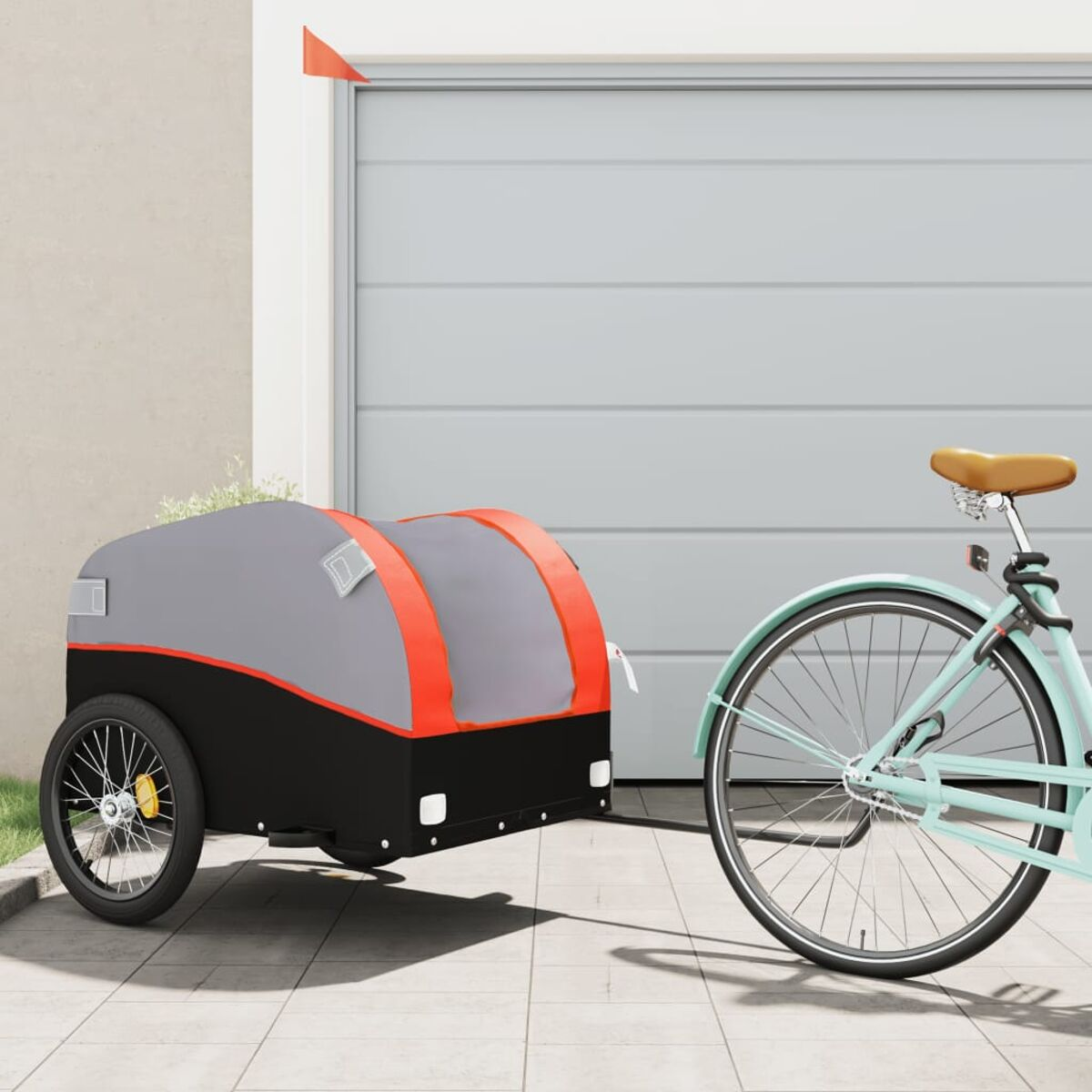 Ein Fahrrad zieht einen grau-roten Anhänger vor einer Garage.