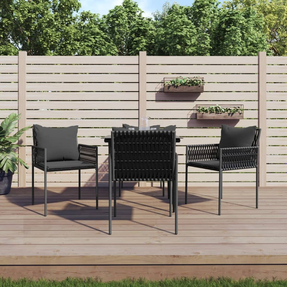 Essgruppe im Freien mit schwarzen Stühlen und einem Tisch. Schwarze Kissen und Holzdeck-Hintergrund.
