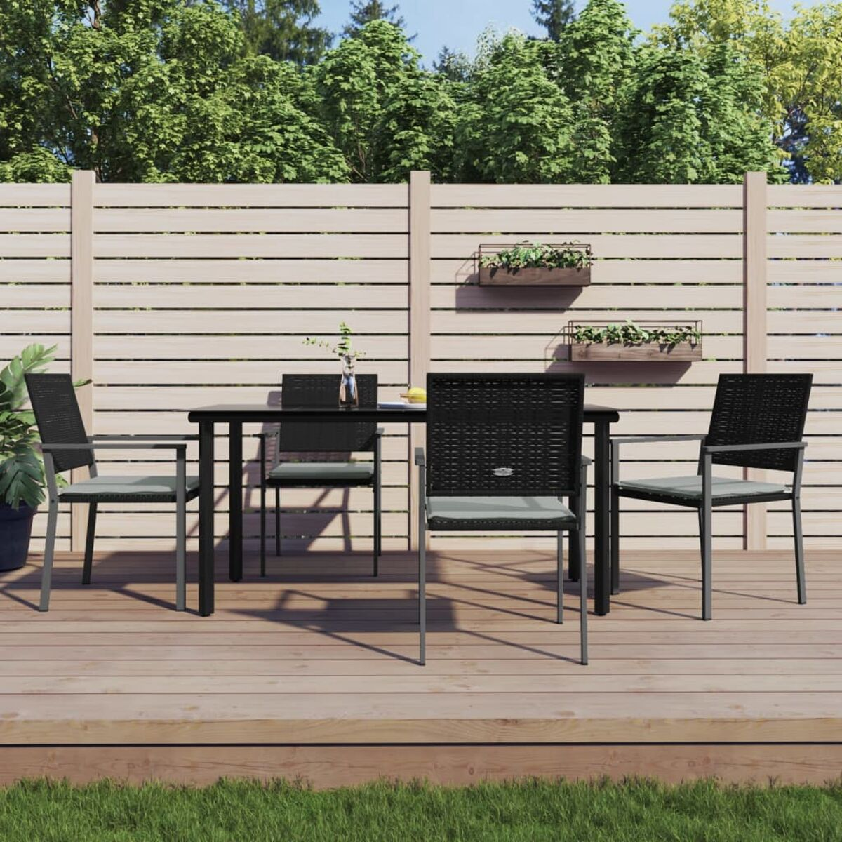 Essgruppe im Freien auf Holzterrasse, Tisch, Stühle und Grün.