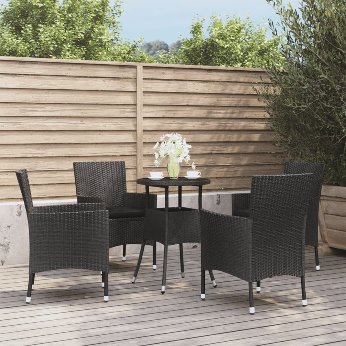 Outdoor-Sitzbereich mit Tisch und vier schwarzen Korbstühlen.