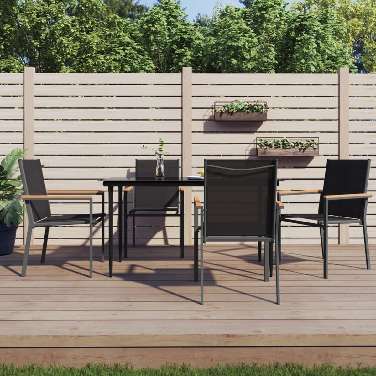 Ein Esszimmer-Set im Freien auf einer Holzterrasse. Enthält einen schwarzen Tisch, Stühle und einen Holzzaun.