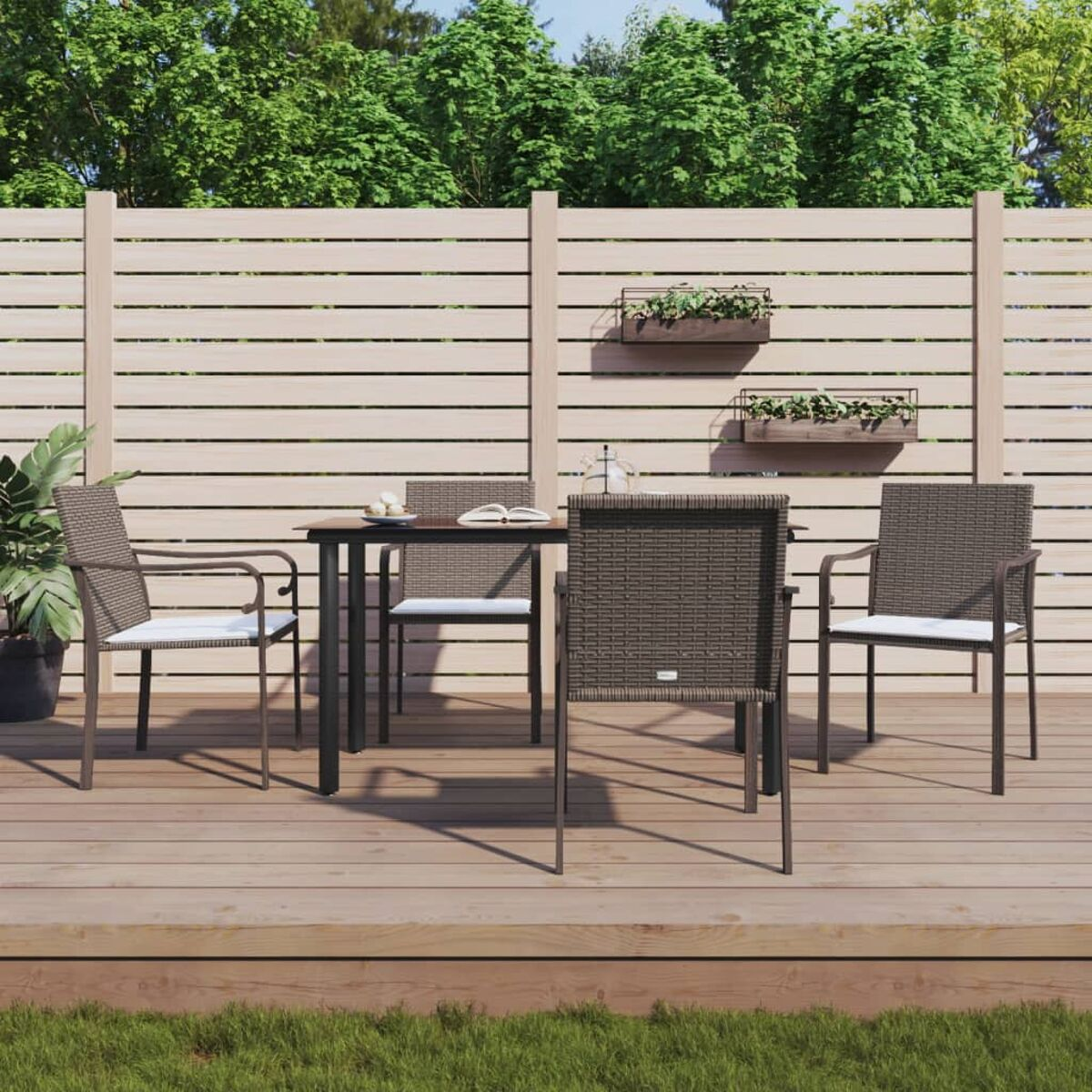 Ein Terrassenset mit Tisch und Stühlen auf einem Holzdeck. Der Hintergrund hat Bäume und einen Zaun.
