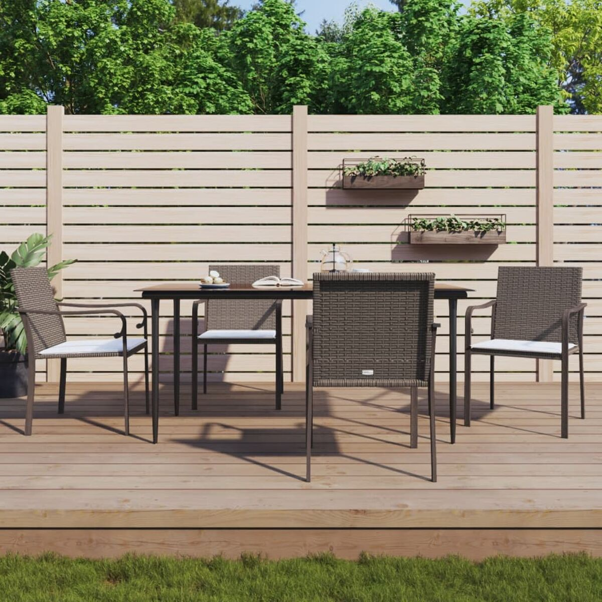 Essgruppe im Freien auf Holzterrasse. Tisch mit Stühlen, grüne Pflanzen und Holzzaun.