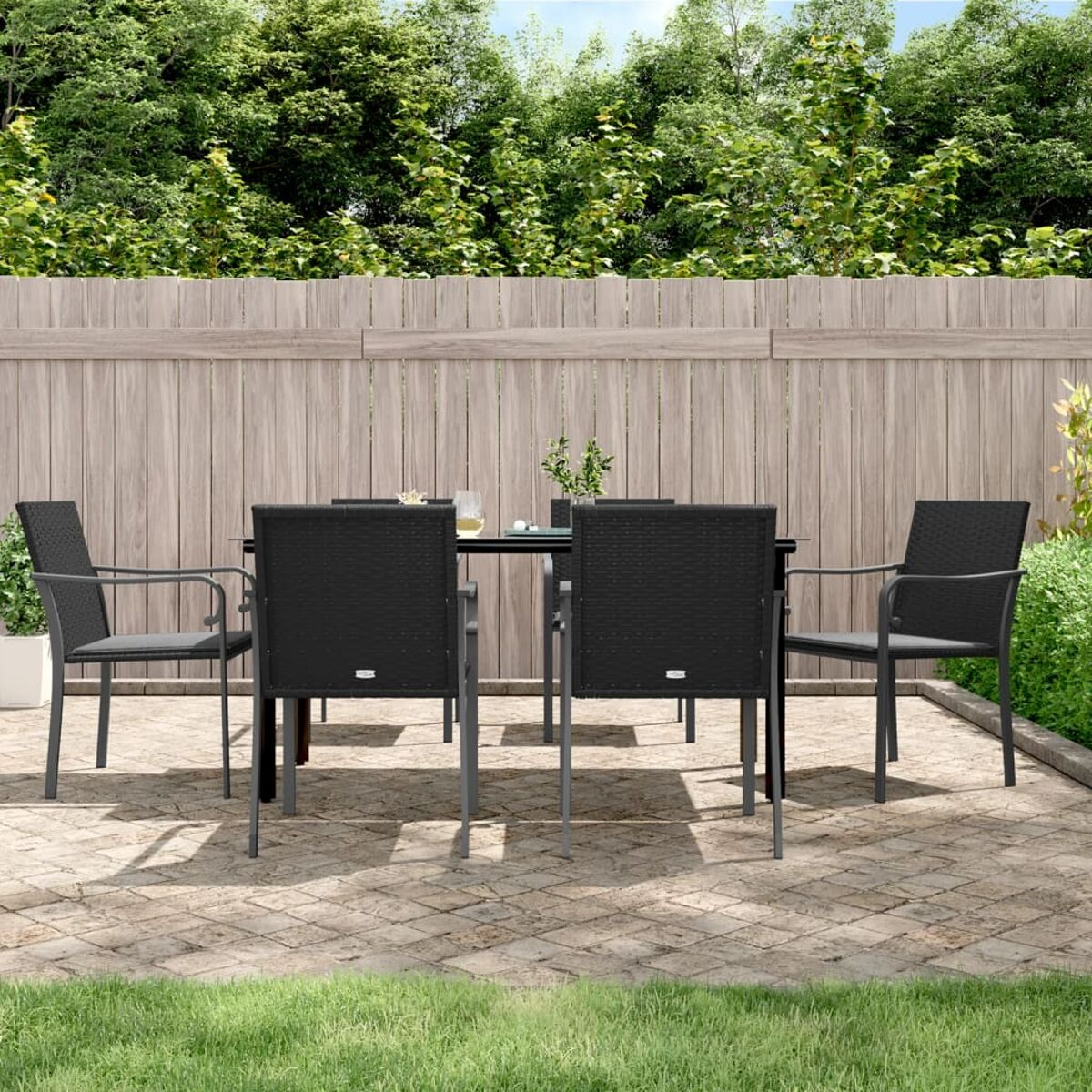 Essgruppe für den Außenbereich mit schwarzem Tisch und vier Stühlen. Das Set steht auf einer Ziegelterrasse.