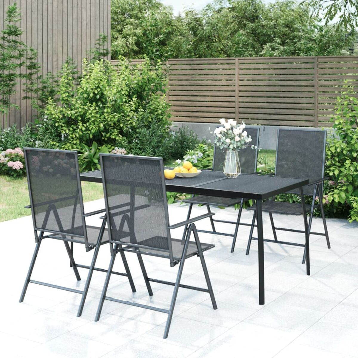 Essgruppe im Freien mit schwarzem Tisch und Stühlen. Garten im Hintergrund.