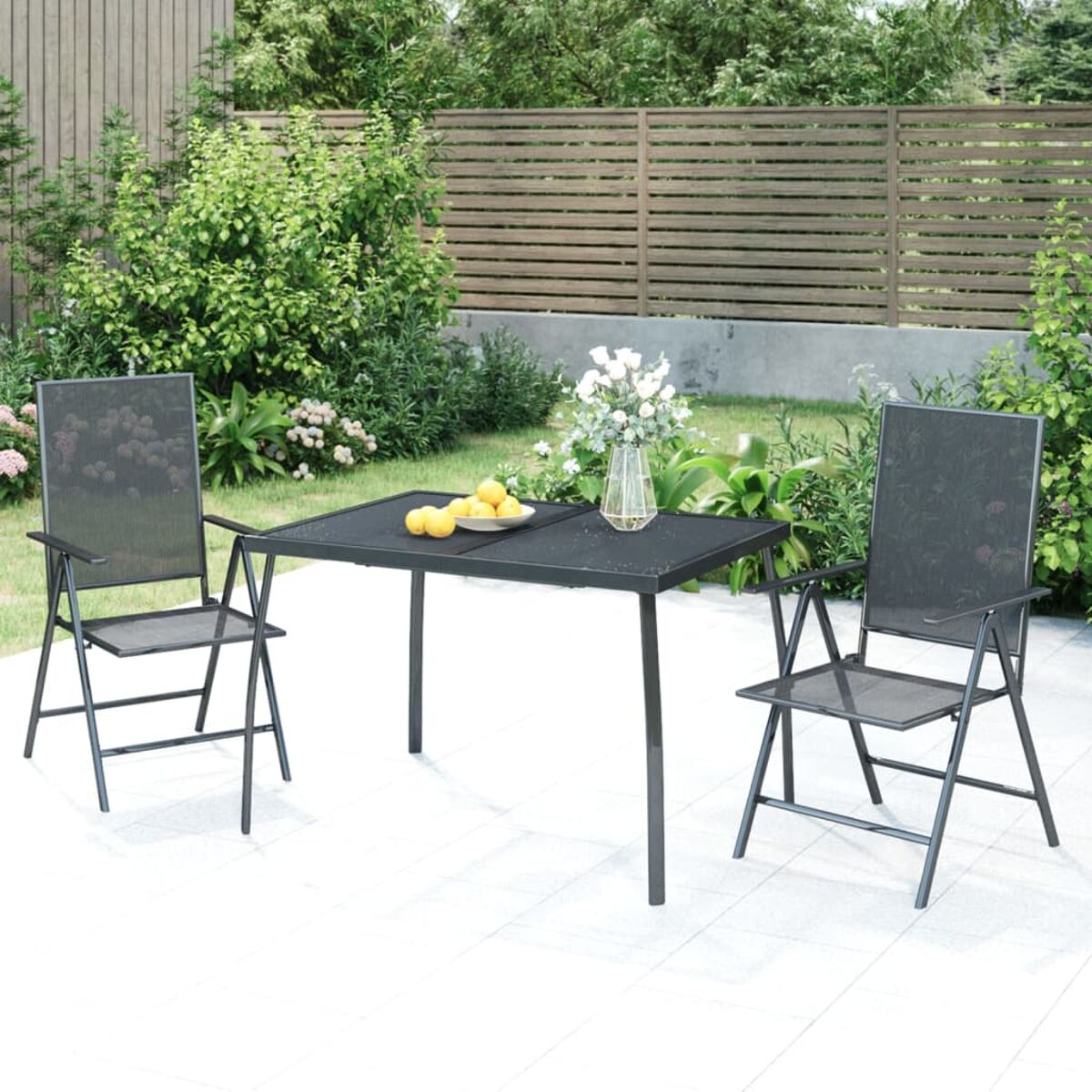 Essgruppe im Freien mit schwarzem Tisch und Stühlen. Zitronen und Blumen auf dem Tisch.