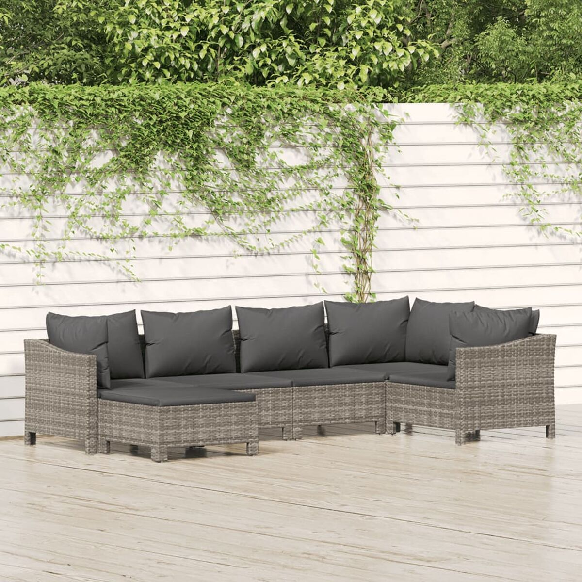 Terrassenset mit Sofa und Grün. Holzboden und weiße Wand im Hintergrund.