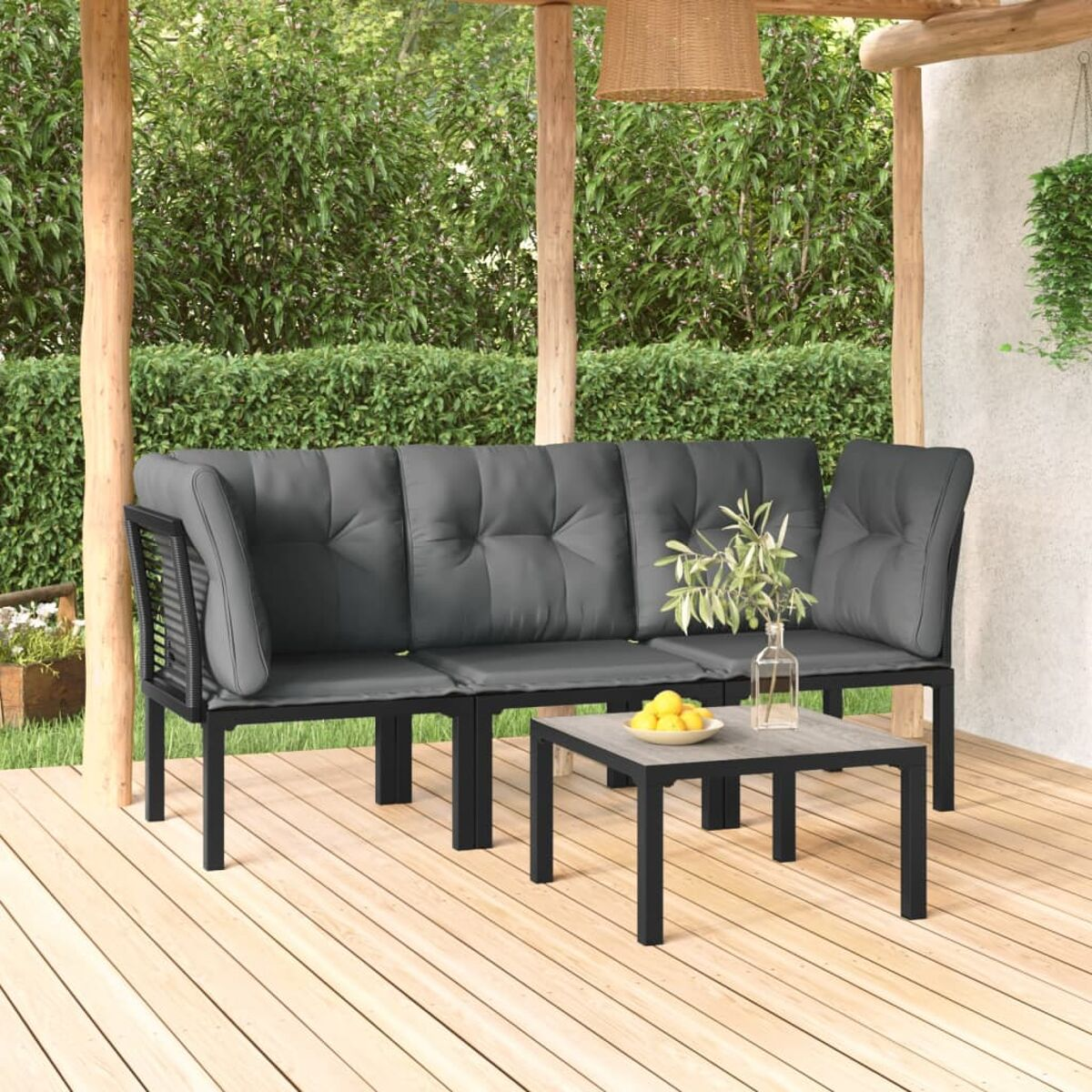 Outdoor-Terrassenset mit grauen Kissen und schwarzem Rahmen. Kleiner Tisch davor. Holzdeck und Pflanzen.