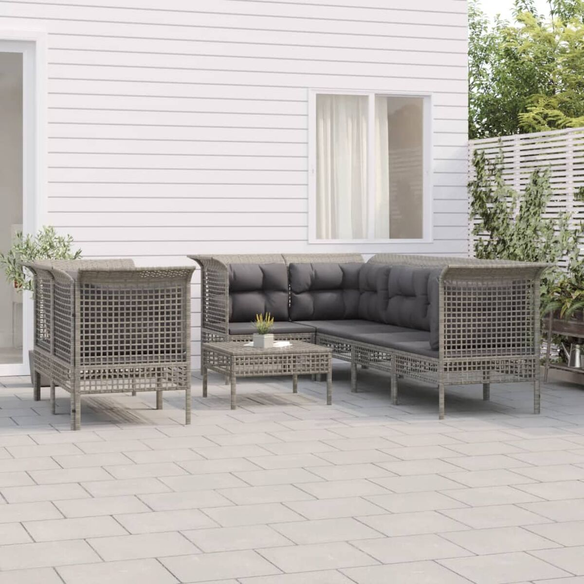 Terrassenset für den Außenbereich mit Sofa, zwei Stühlen und einem Tisch. Das Set ist aus Korbgeflecht.