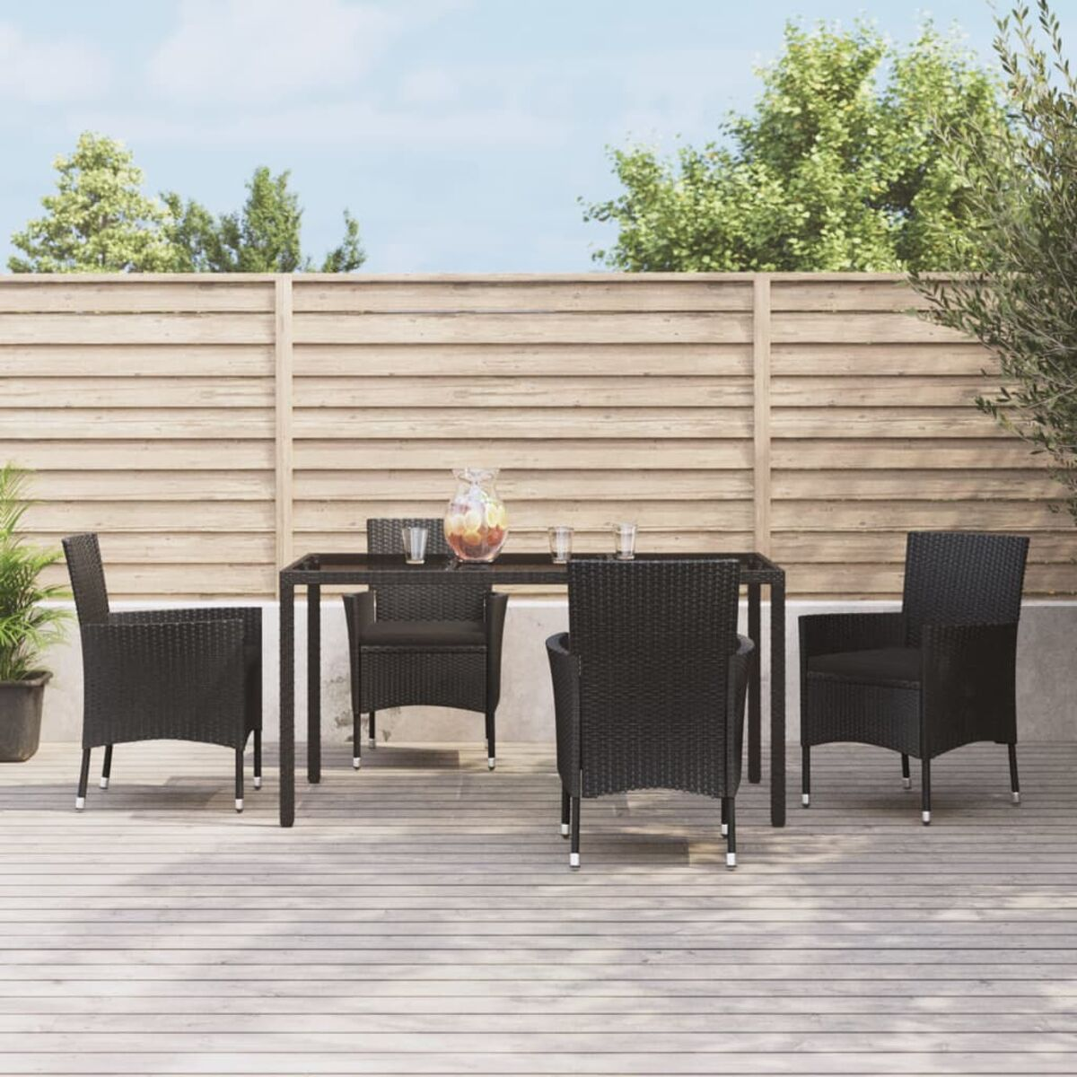 Essgruppe im Freien. Schwarze Stühle um einen Tisch, Holzterrasse, Holzzaun.