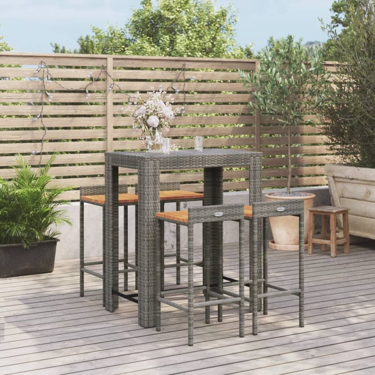Outdoor-Bar-Set mit grauem Tisch und Hockern. Holzterrasse und Pflanzen sichtbar.