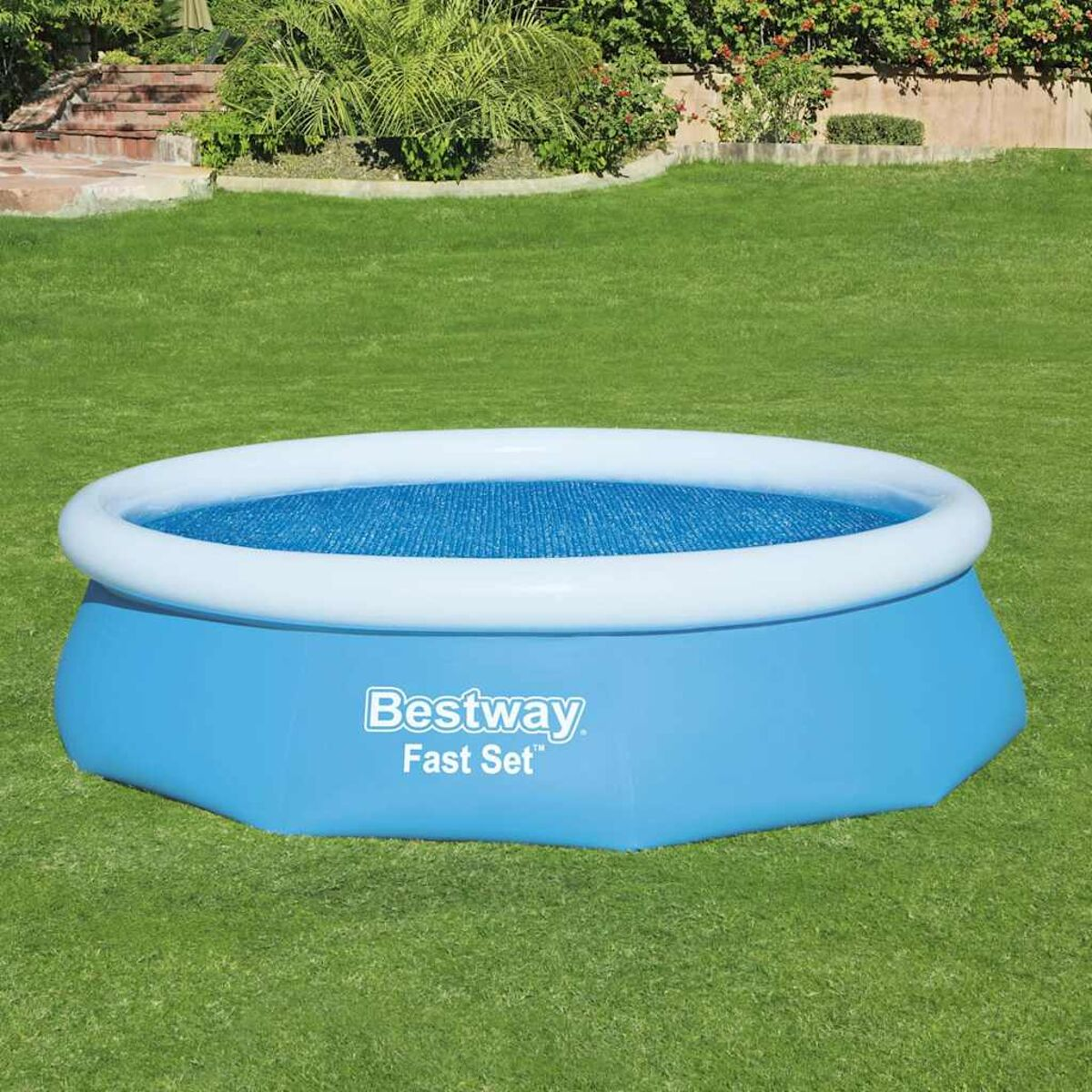 Blauer, runder, aufblasbarer Pool auf grünem Gras. Er hat einen weißen Rand und ein blaues Innere.