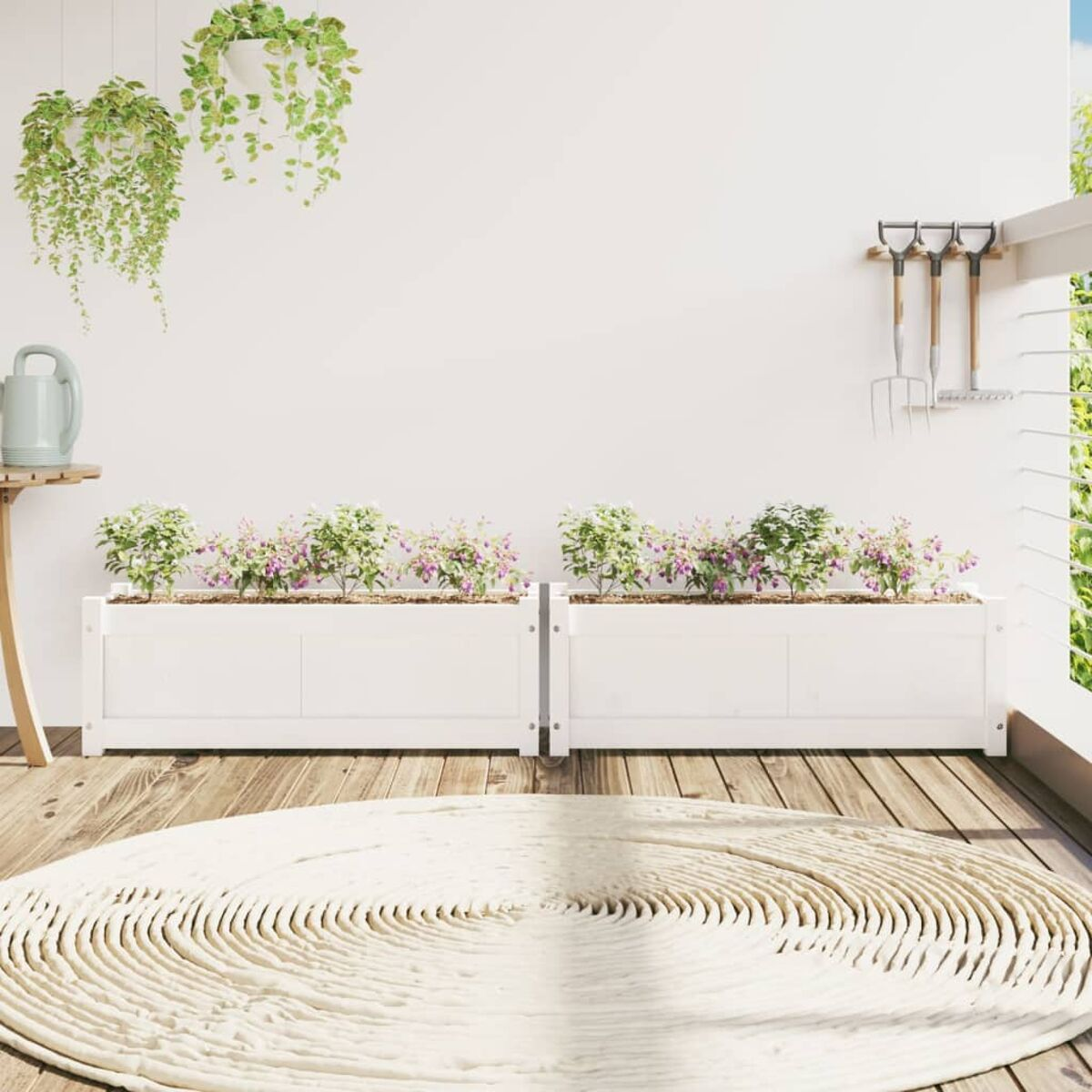 Zwei weiße Holzpflanzgefäße auf einem Holzdeck mit Blumen und Hängepflanzen. Werkzeuge hängen darüber.