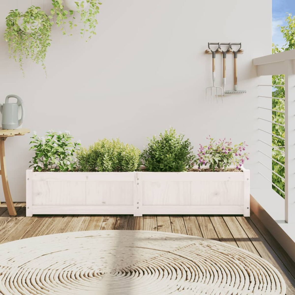 Zwei weiße Holzblumentöpfe mit Pflanzen und Gartengeräten auf einem Deck. Weiße Wand und Geländer im Hintergrund.