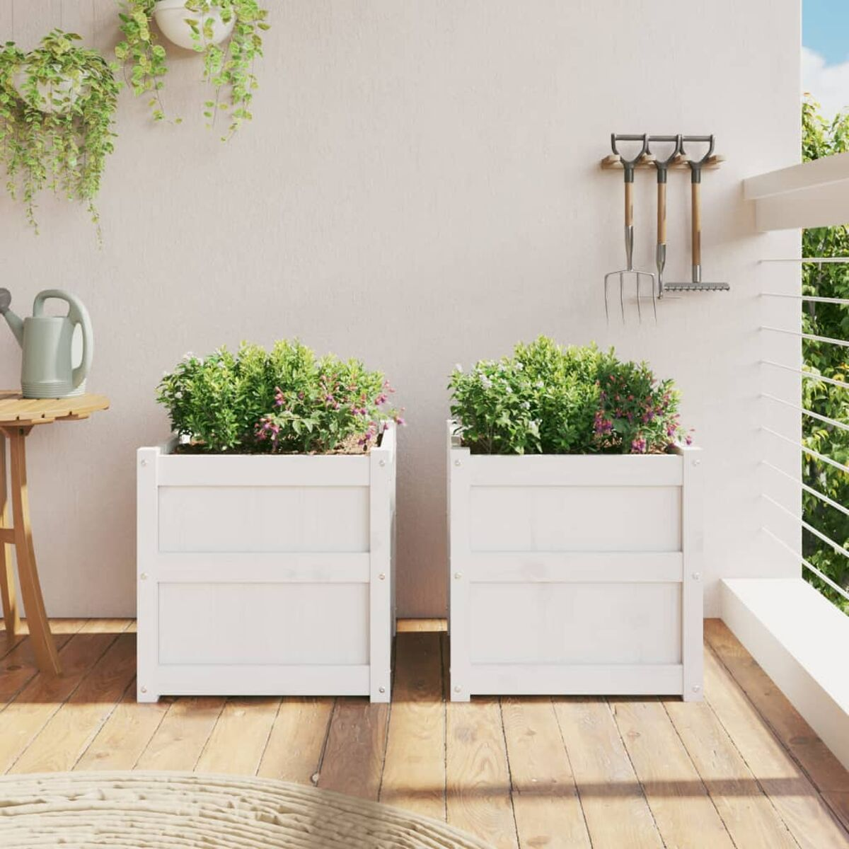Zwei weiße Holzpflanzgefäße mit grünen Pflanzen und Blumen auf einem Holzdeck mit weißer Wand.