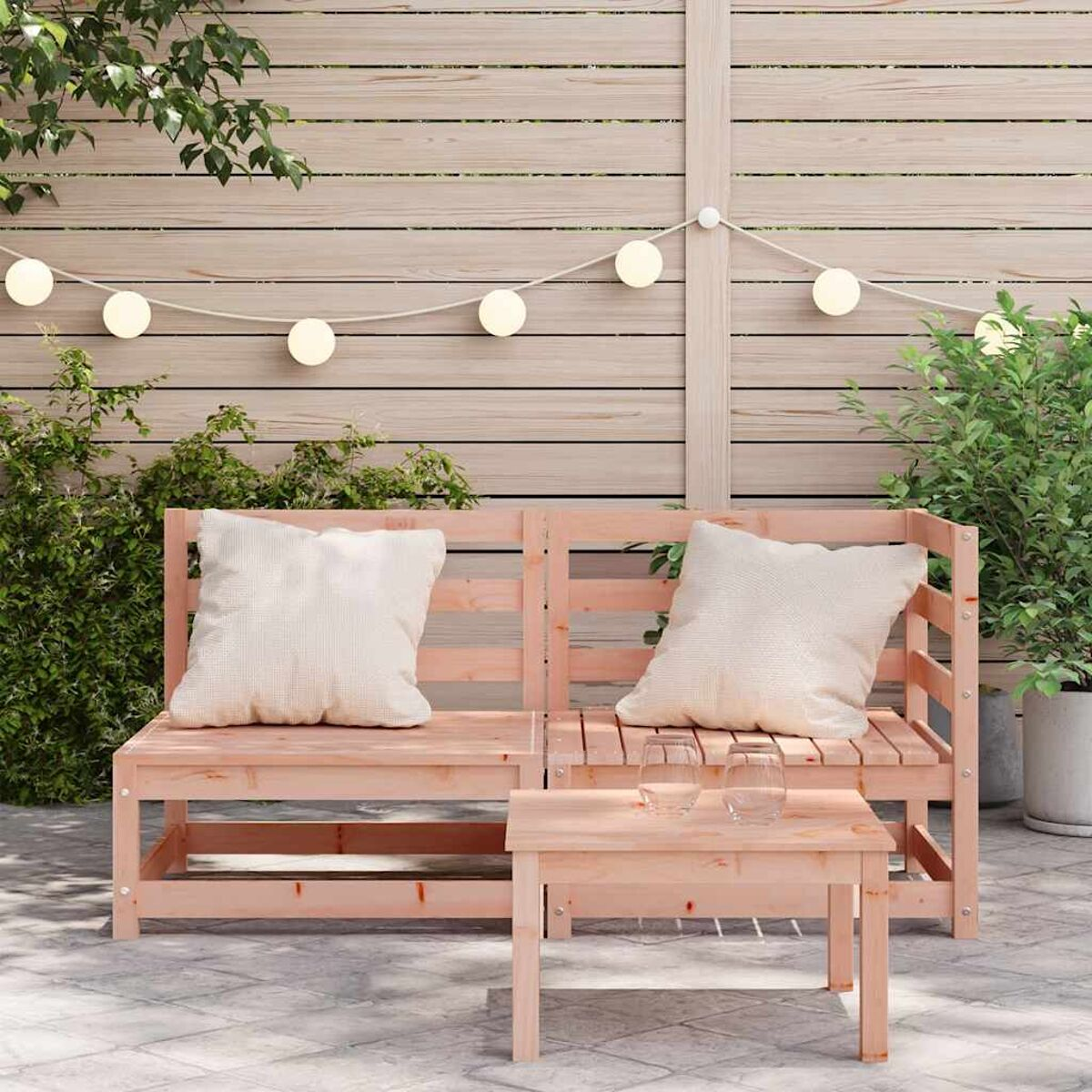 Holzbank mit Kissen, kleinem Tisch und Lichterketten im Freien.