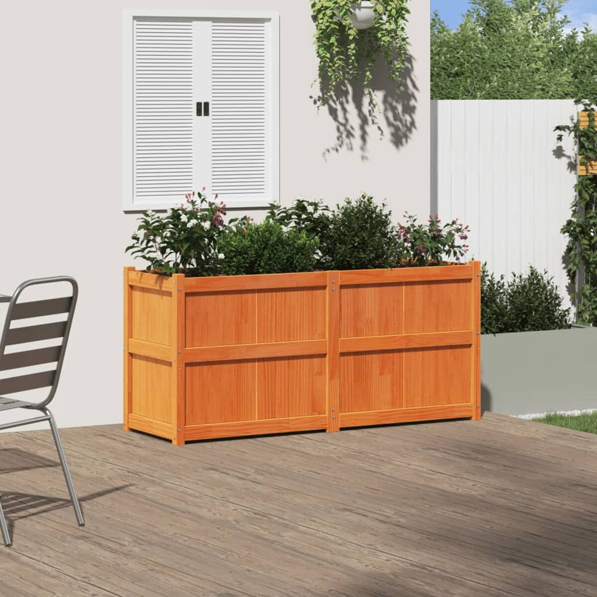 Eine hölzerne Pflanzkasten gefüllt mit Pflanzen. Sie steht auf einer Holzterrasse in der Nähe eines Hauses.