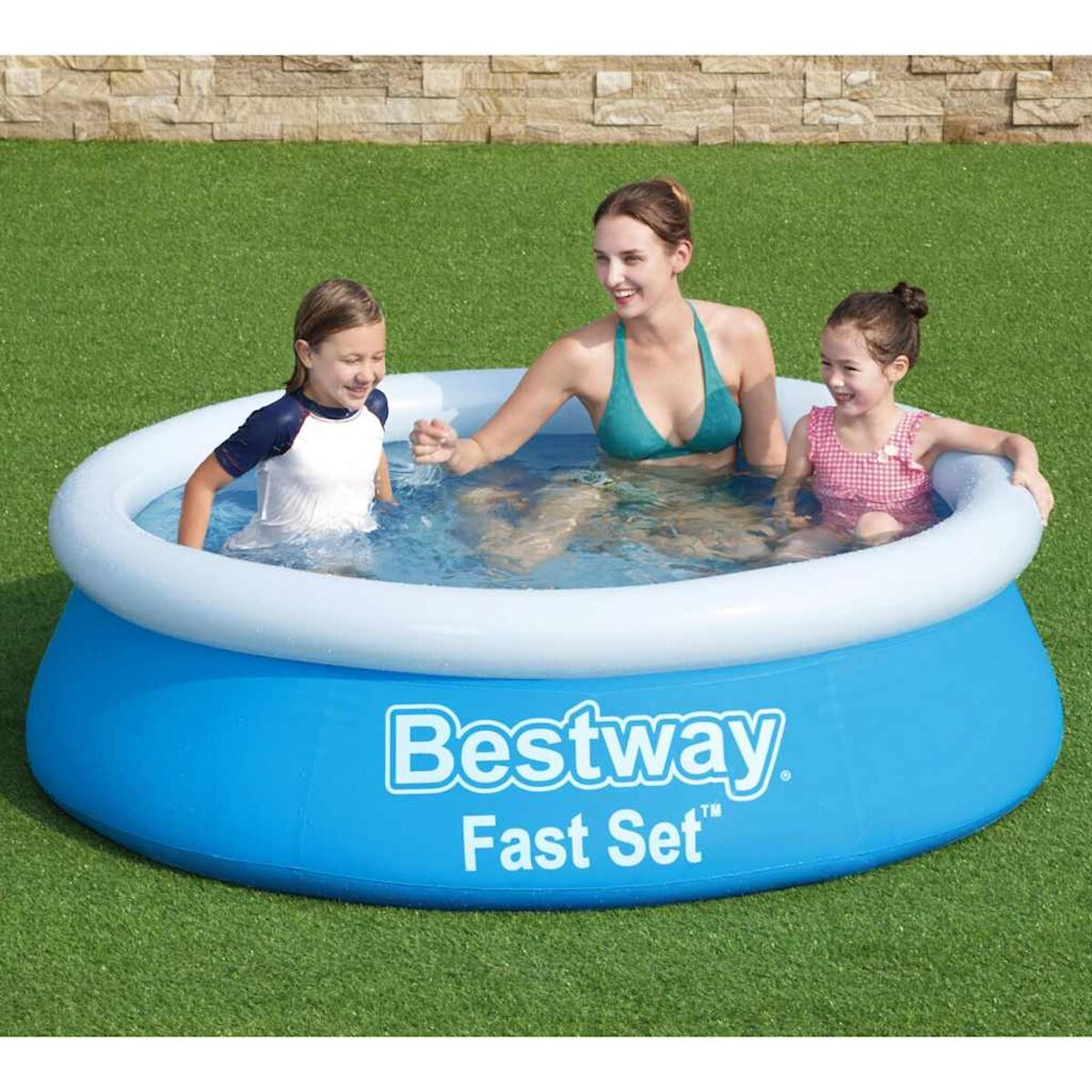 Drei Personen in einem blauen aufblasbaren Pool auf grünem Gras. Eine Frau und zwei Kinder sind drin.