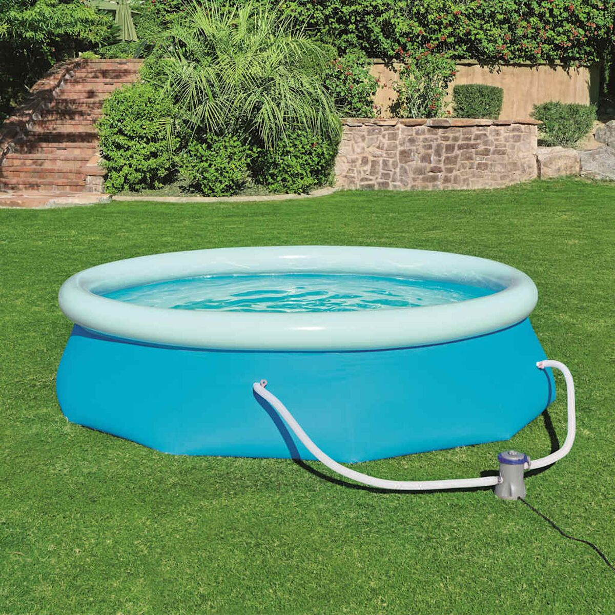 Blauer aufblasbarer Pool mit Wasser gefüllt, mit weißem Rand. Er steht auf einem grünen Rasen, eine Pumpe ist angebracht.