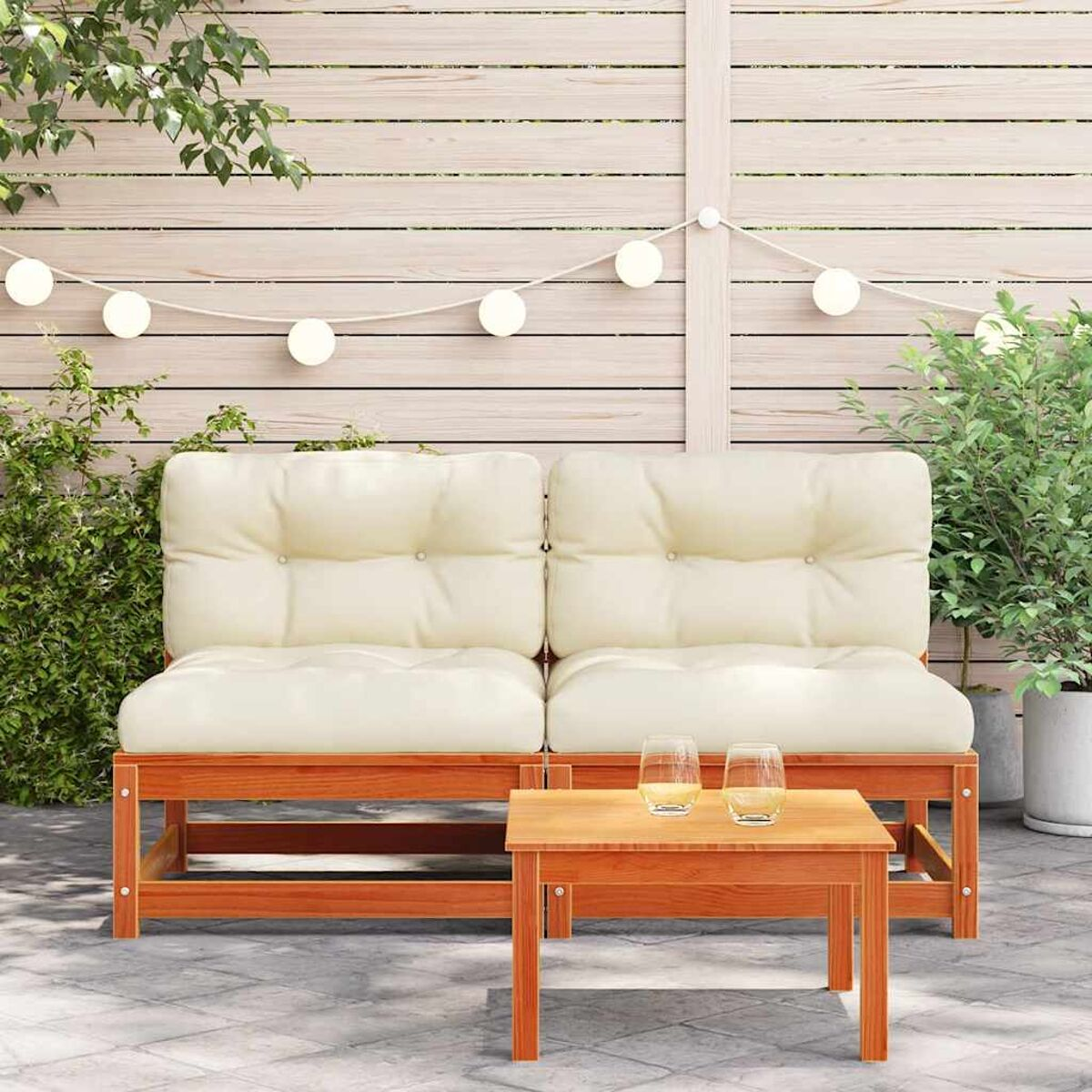 Holz-Outdoor-Sofa mit weißen Kissen und Couchtisch. Lichterketten im Hintergrund.