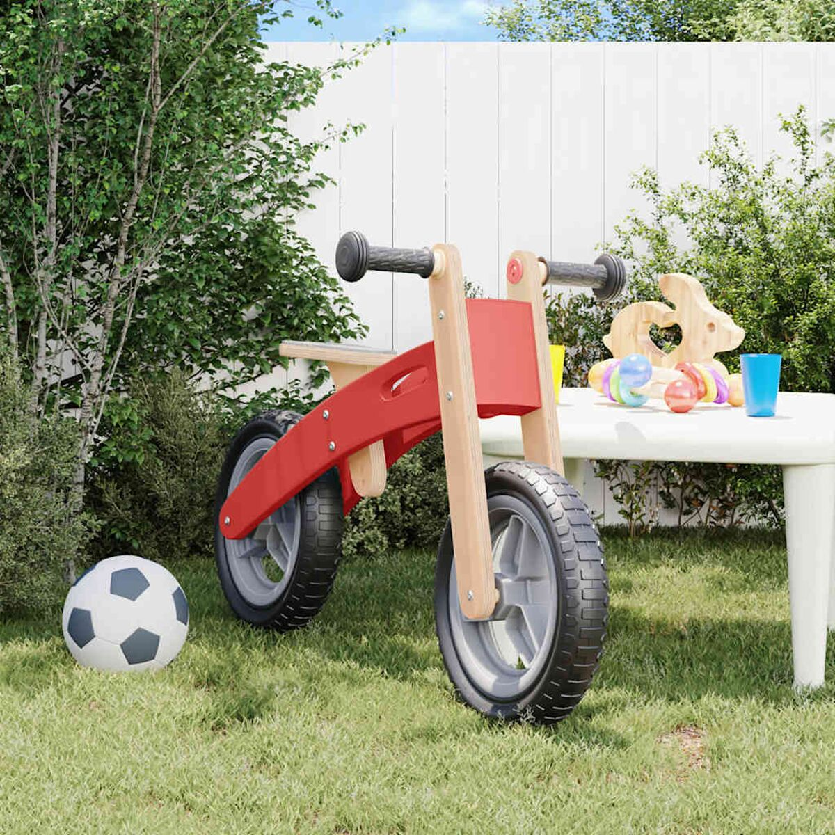 Ein rotes und Holz-Laufrad, ein Fußball und Spielzeug auf einem Tisch.