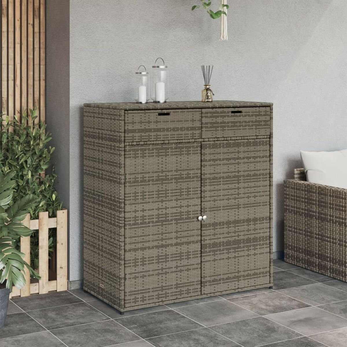 Korbschrank mit zwei Türen, zwei Schubladen oben, Kerzen und einer Pflanze.