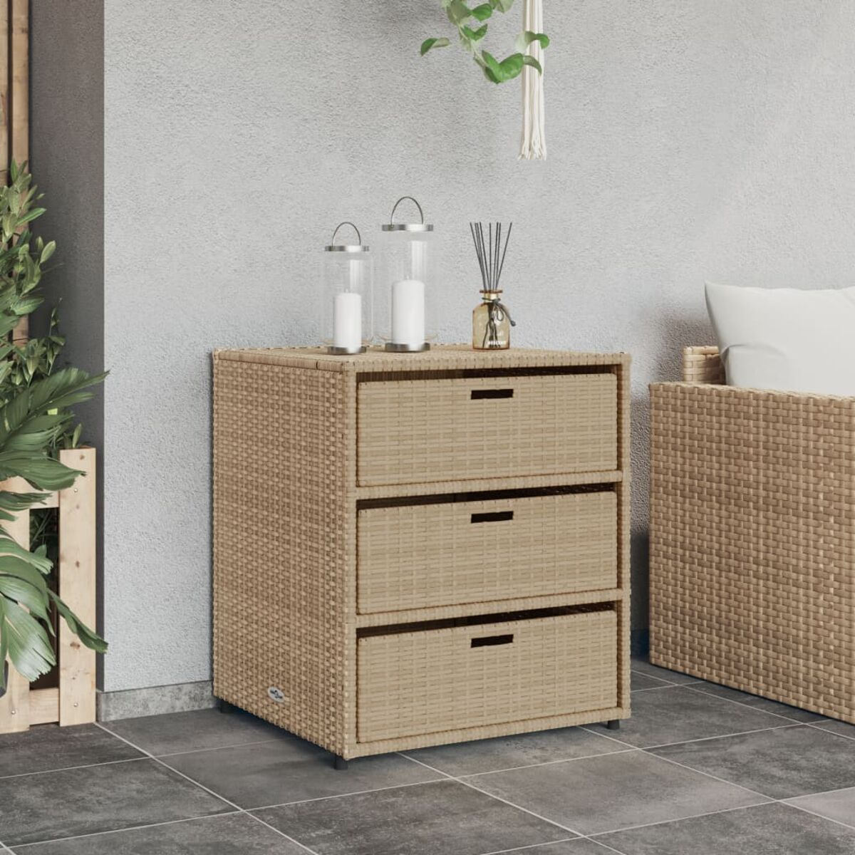 Ein Weidenholzschrank mit drei Schubladen. Oben stehen zwei Kerzen und eine Vase. Rechts ist ein Weidenholzsofa.