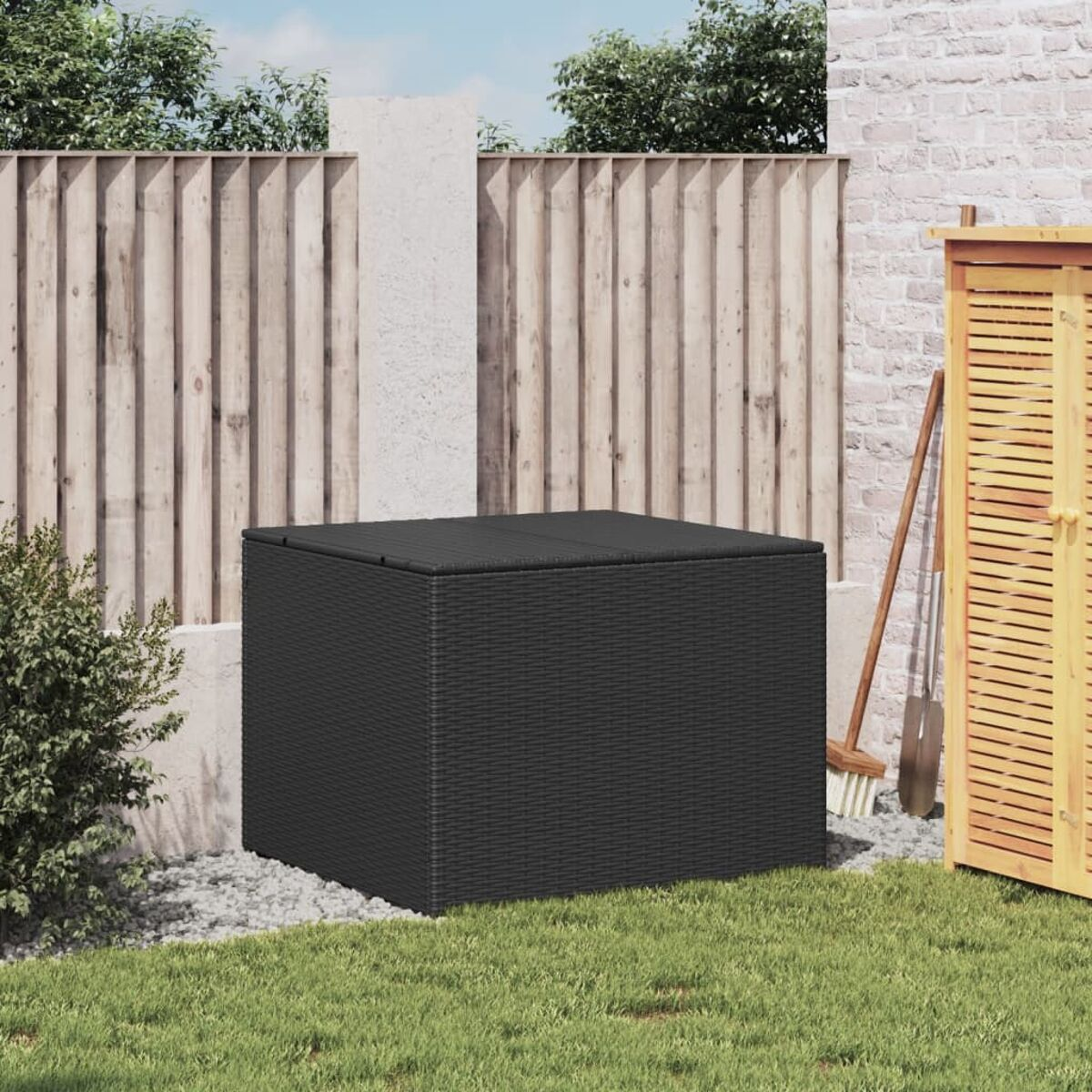 Eine schwarze Aufbewahrungsbox auf dem grünen Gras. Der Hintergrund zeigt einen Holzzaun.