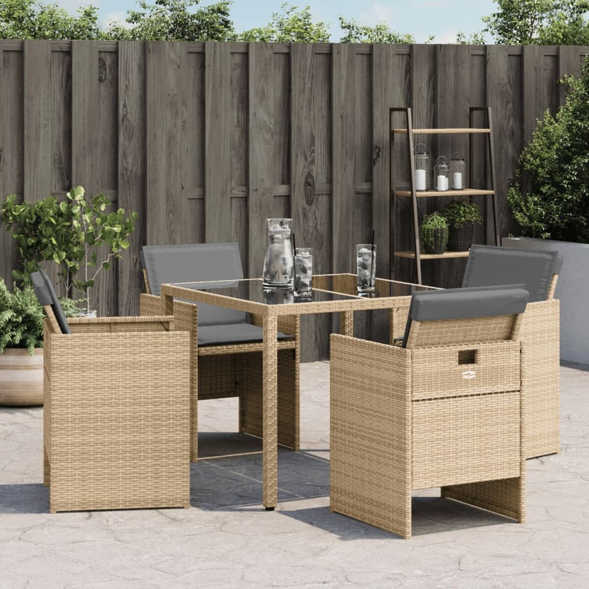 Ein Terrassenset mit Glastisch und vier Stühlen. Gläser und eine Kanne stehen auf dem Tisch.