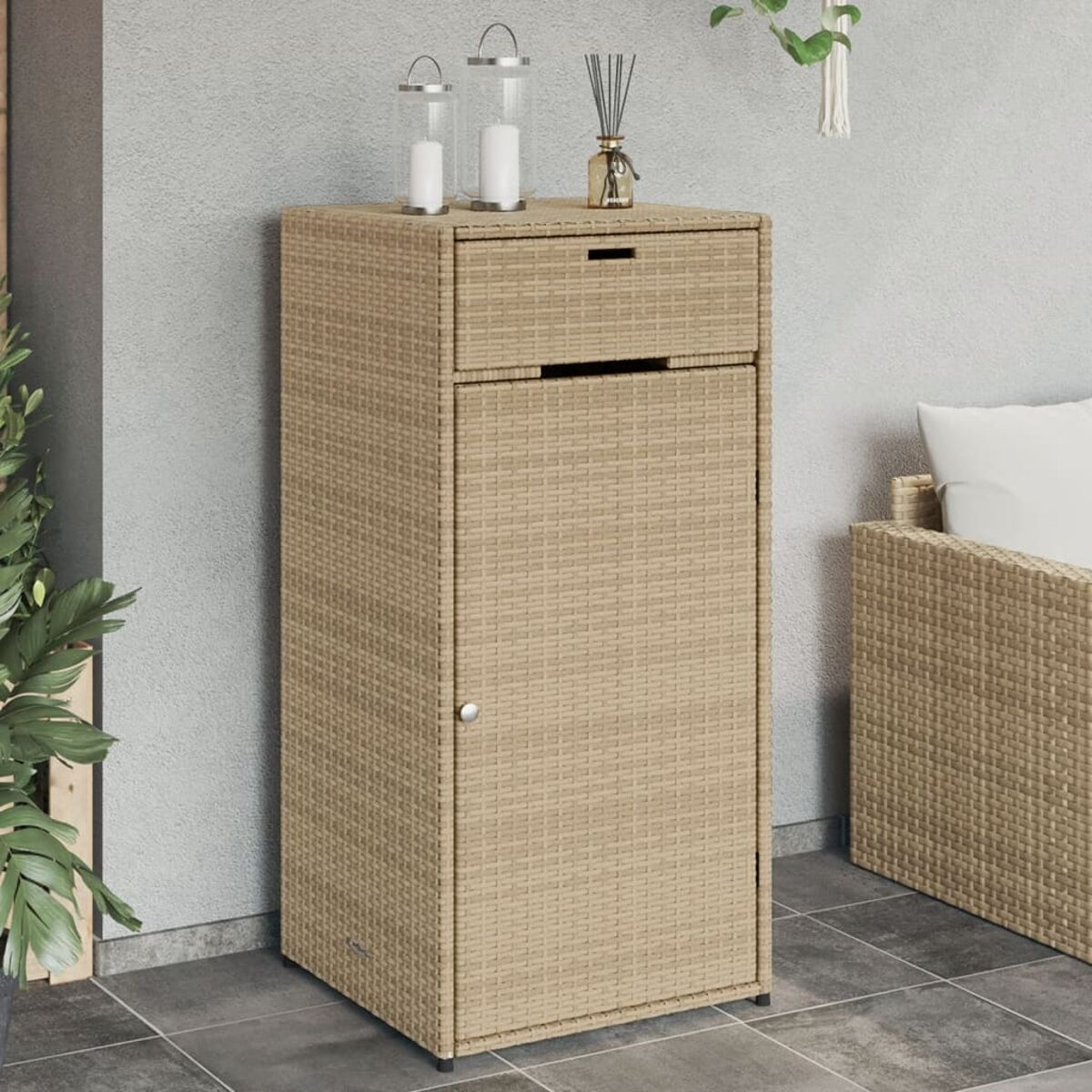 Beigefarbener Korbschrank mit Schublade, Tür und kleinem Tisch mit Kerzen.