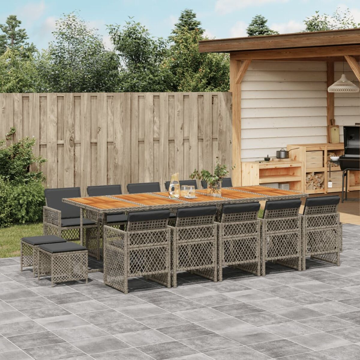 Rattan Essgruppe im Freien mit Tisch, Stühlen und Kissen auf einer Terrasse, Garten im Hintergrund.
