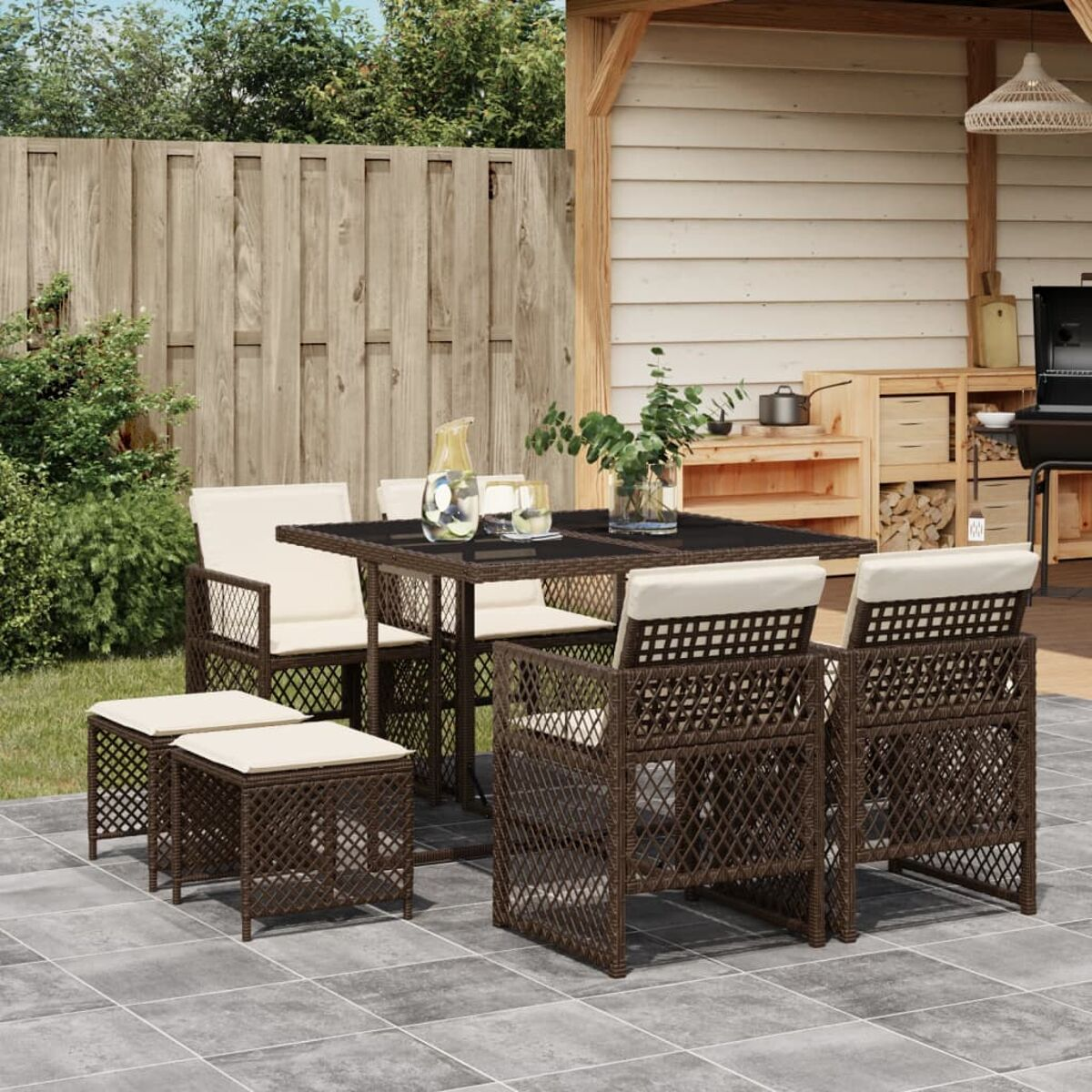 Terrassenecke mit braunen Möbeln, Tisch und Hockern, auf grauen Fliesen, Gartenumgebung.