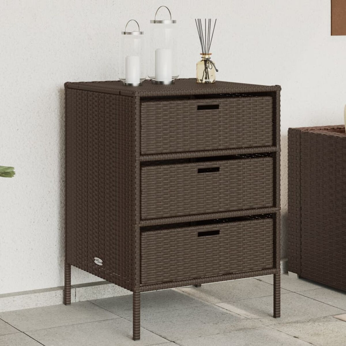 Brauner Rattan-Schrank mit drei Schubladen. Zwei Kerzen und ein Diffusor sind oben.