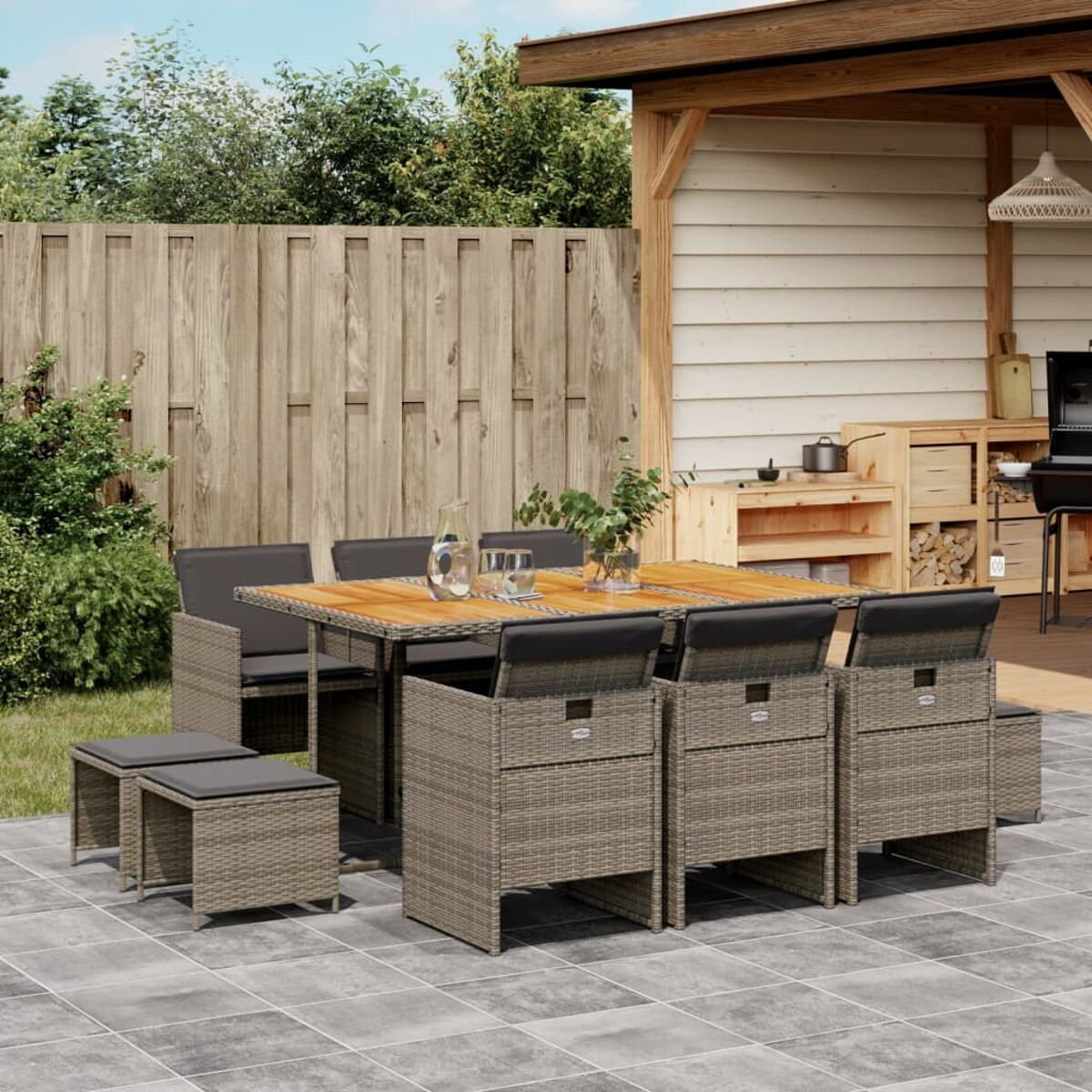 Essgruppe im Freien. Brauner gewebter Tisch, Stühle und Hocker. Holzterrasse.