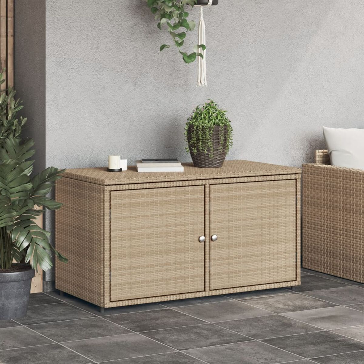 Wickerschrank mit zwei Türen. Oben befinden sich Pflanzen und eine Kerze. Der Hintergrund ist eine graue Wand.