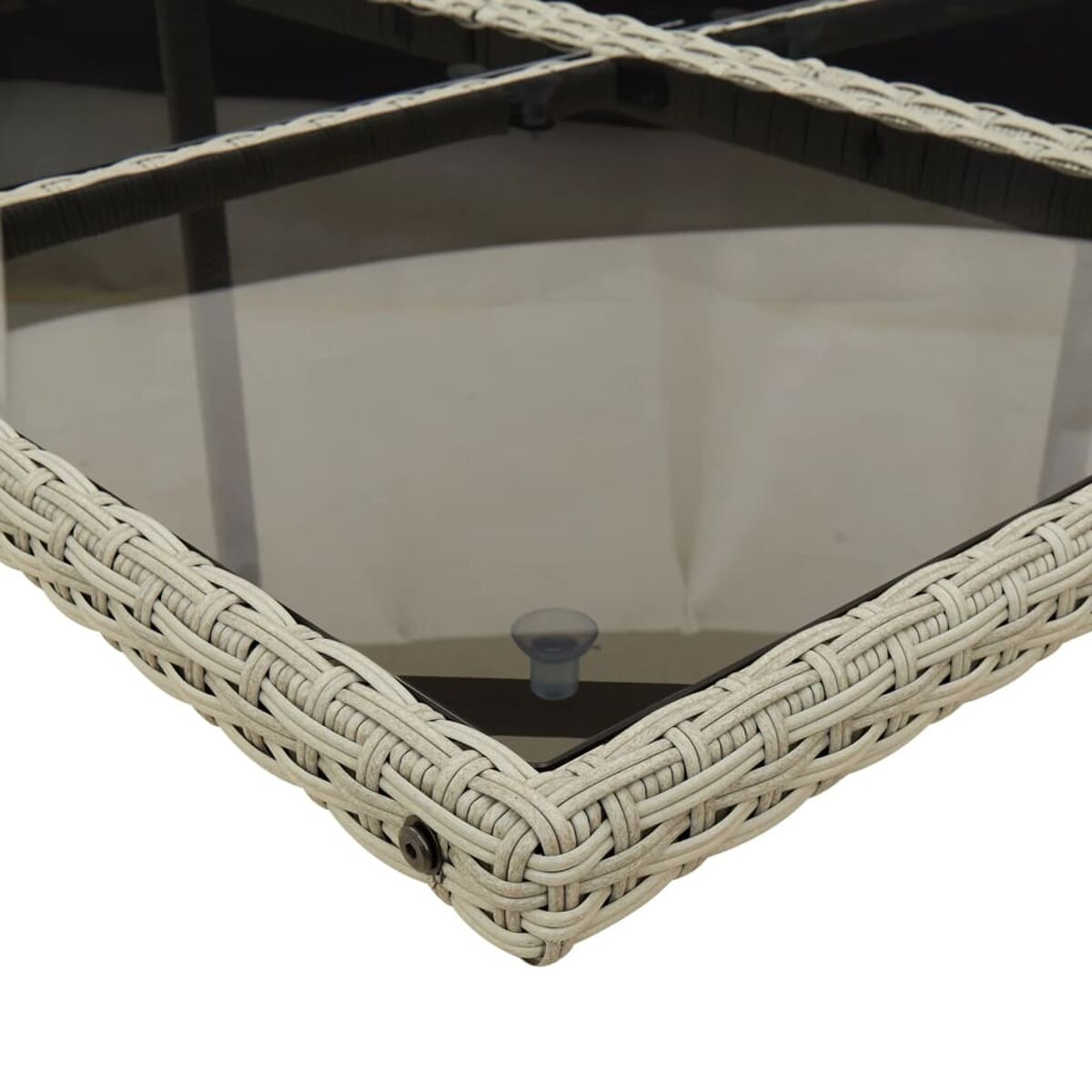 Primo piano di un angolo di tavolo bianco intrecciato con piano in vetro trasparente. Piede in plastica trasparente.