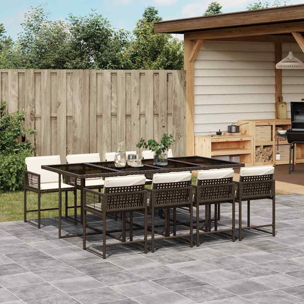 Set da pranzo all'aperto con sedie e tavolo in rattan scuro. Cuscini bianchi. Giardino.