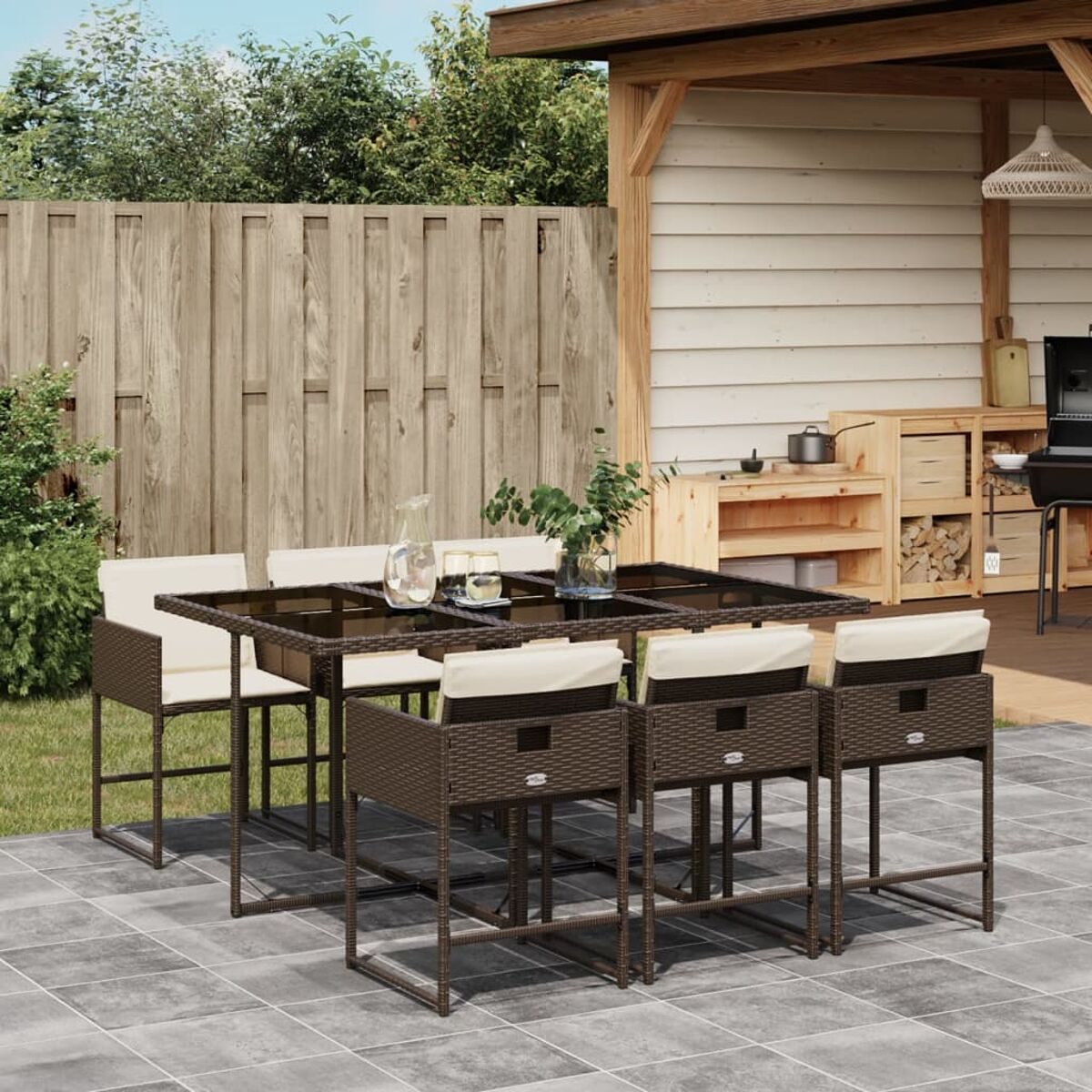 Un set da patio con tavolo rettangolare con piano in vetro e sedie. Include cucina esterna.