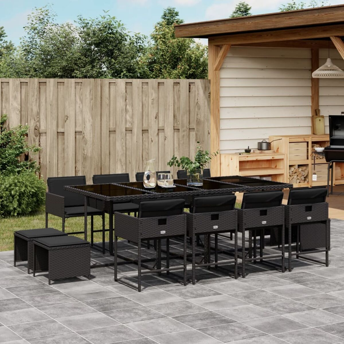 Set da pranzo per esterni su un patio grigio. Il set comprende un tavolo, sedie e una recinzione in legno.