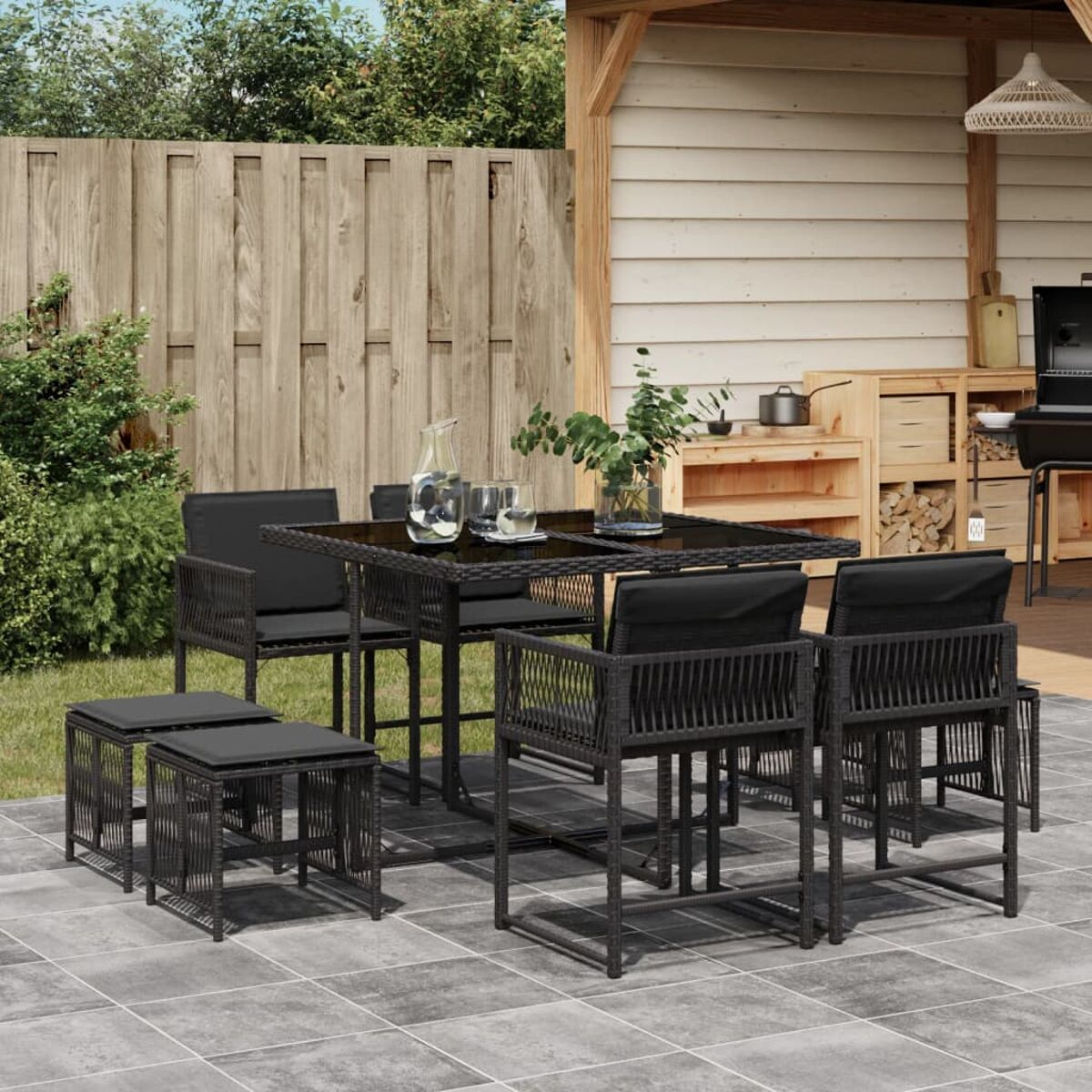 Set da pranzo per esterni con sedie nere, tavolo e pouf. Patio.