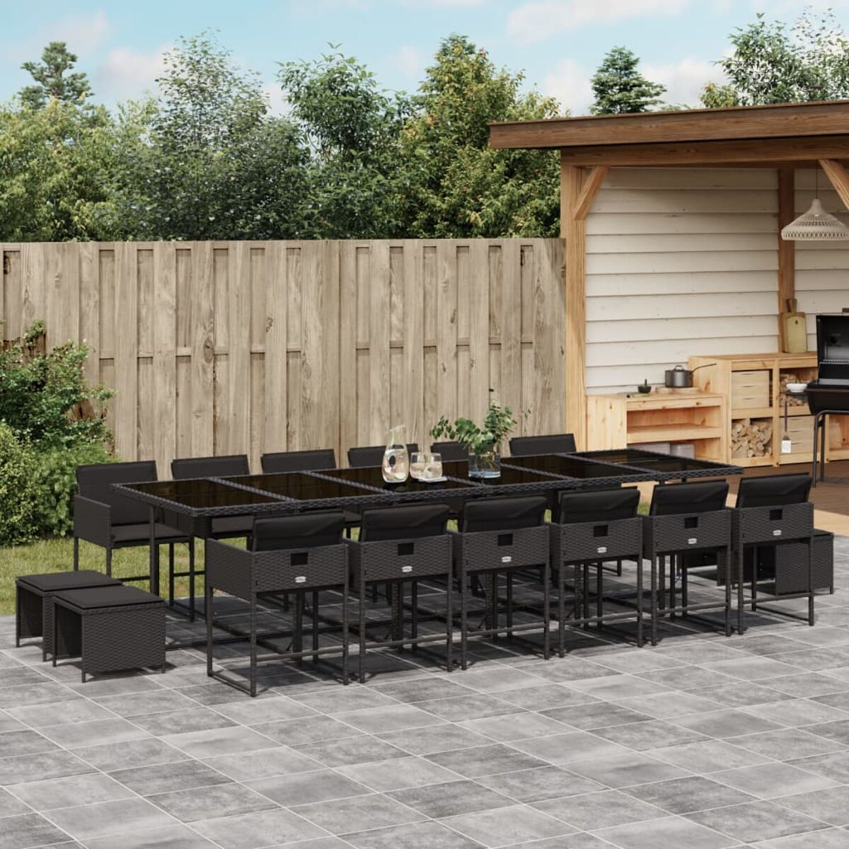 Set patio esterno con mobili neri, tavolo, sedie e pergola in legno.