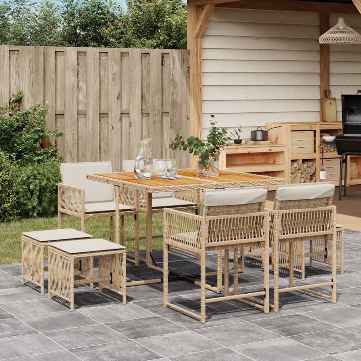 Set da pranzo per esterni con tavolo, sgabelli e sedie con cuscini beige su un patio.