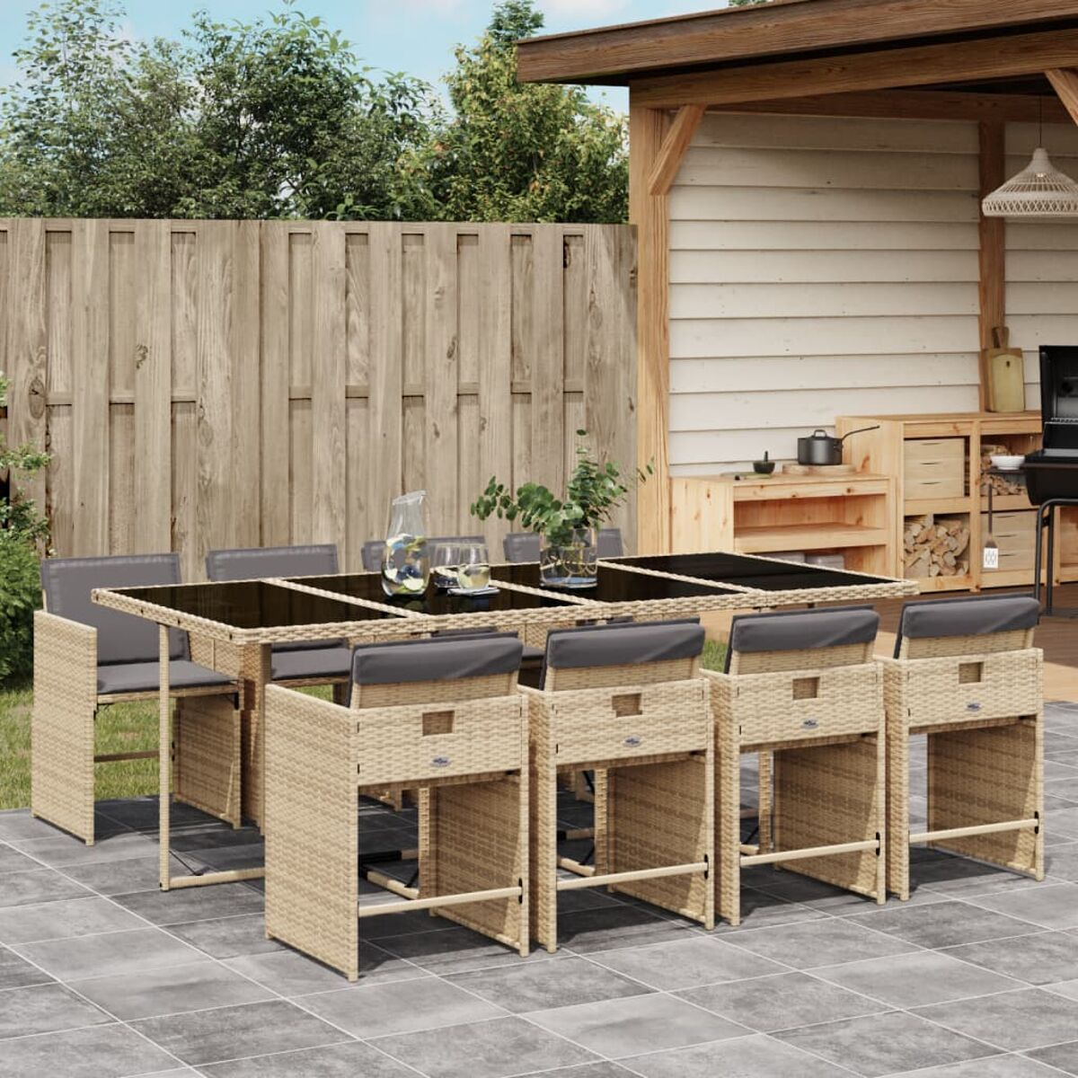 Beiges Korbmöbel-Ess-Set im Freien mit grauen Kissen auf einer gefliesten Terrasse, Holzstruktur im Hintergrund.