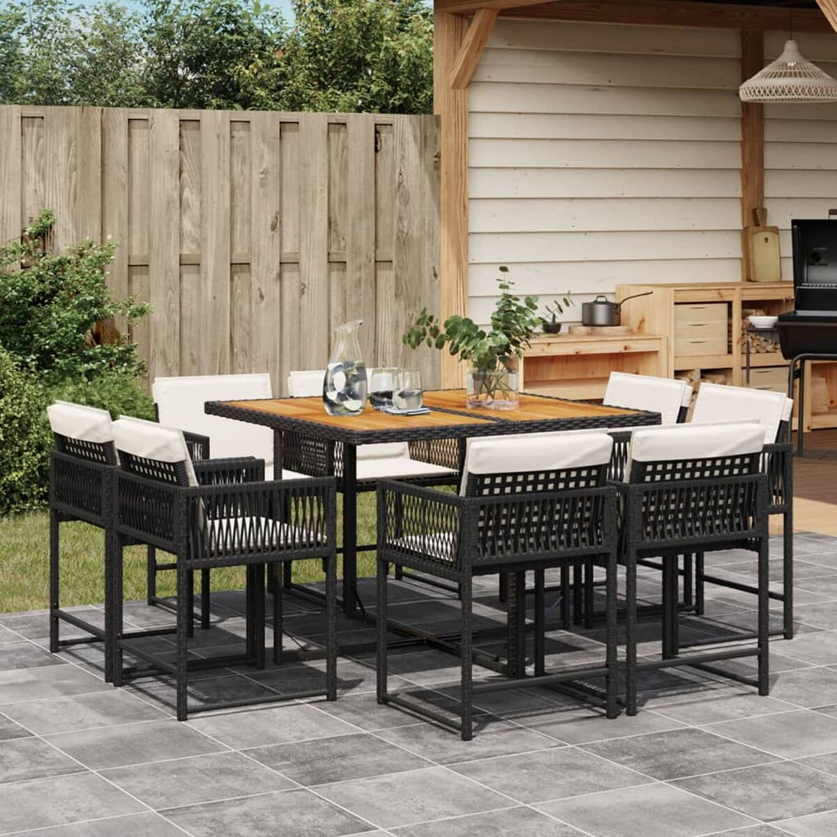 Essgruppe im Freien auf der Terrasse. Enthält Tisch, acht Stühle und Zubehör. Holzzaun im Hintergrund.